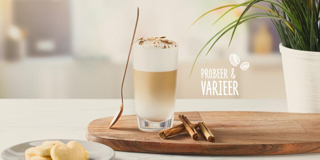 Foto van een Latte Macchiato met kaneel. Tekst op de foto; Probeer & Varieer.